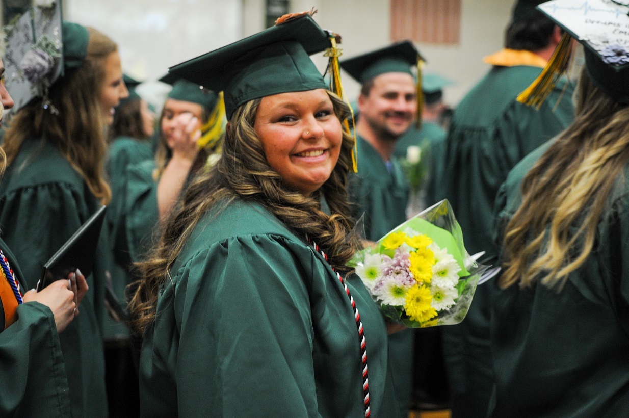 Woman in green cap and gown at graduation ceremony