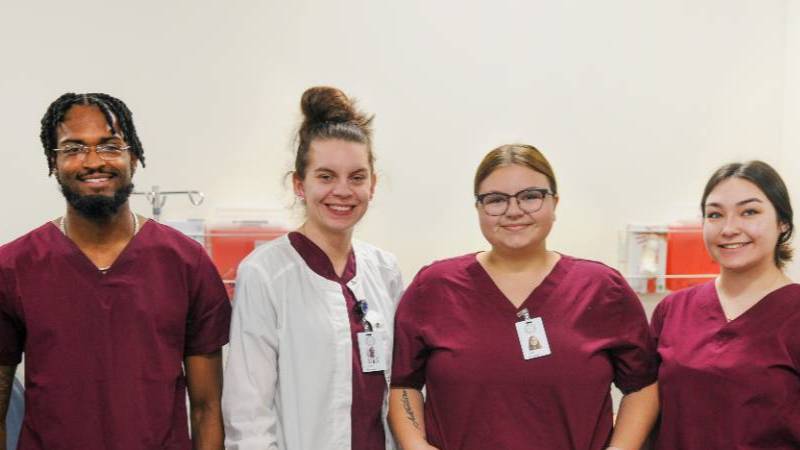 Female and male Allied Health students wearing maroon scrubs