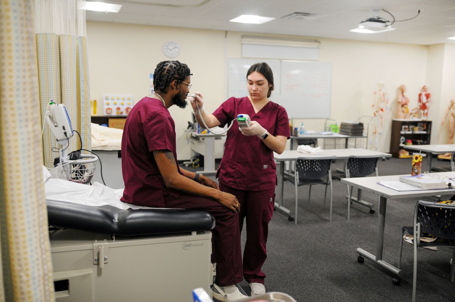 Female student taking the temperature of a male student.