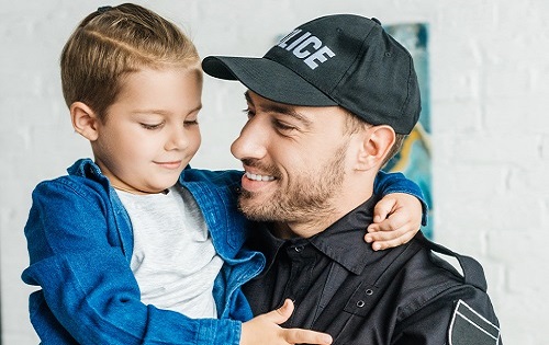 Police officer smiling and holding a small boy