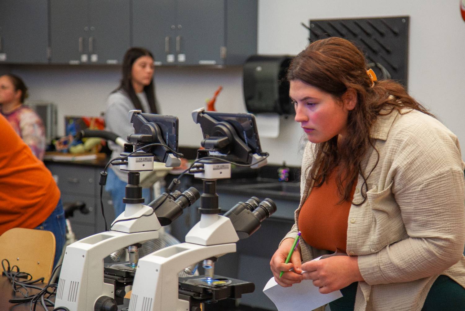female student looking in to microscope in biology classroom
