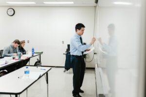 man writing on whiteboard in classroom