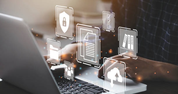 A laptop in a dark setting with white icons floating through the photograph