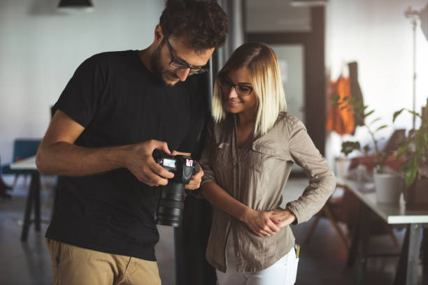 man holding a camera with a zoom lens, standing next to woman