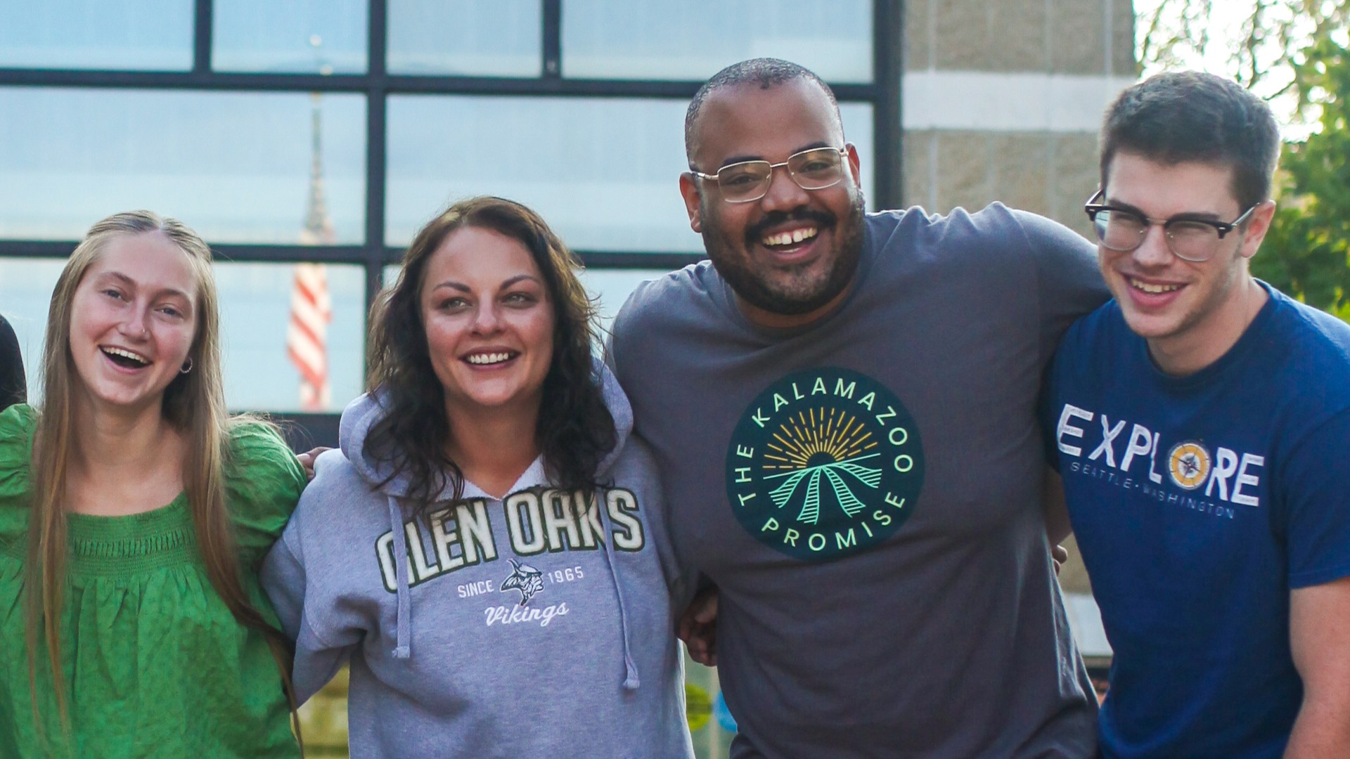 Four students with various age groups standing together in a line and happy
