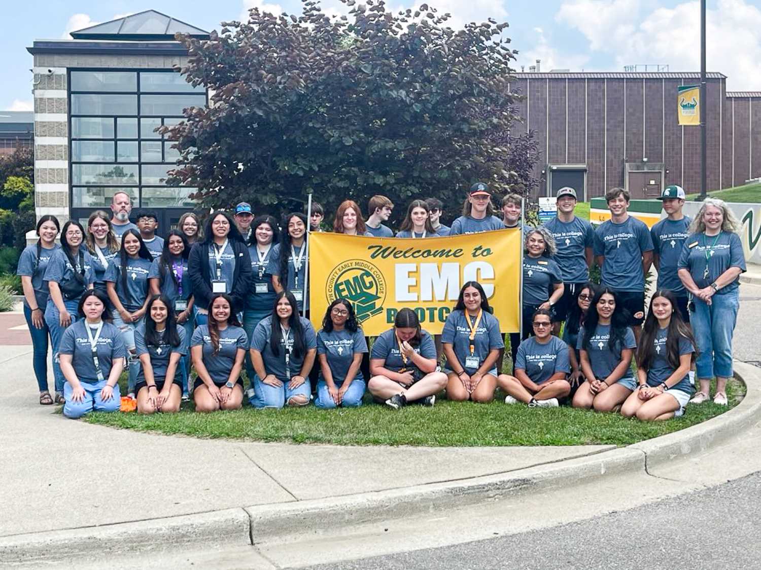Group of EMC students at EMC boot camp sitting on the lawn outside of the main entrance