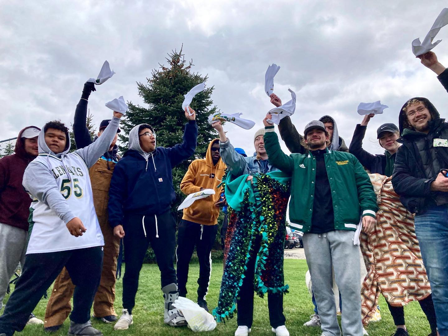 A group of students outside in the fall, all waving white towels