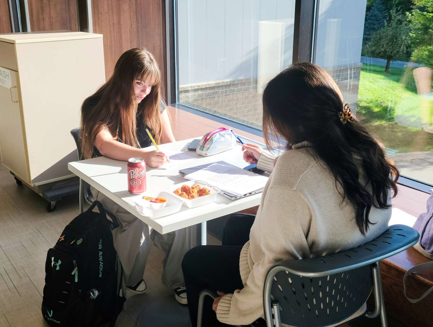 two female students seated at a table and studying 