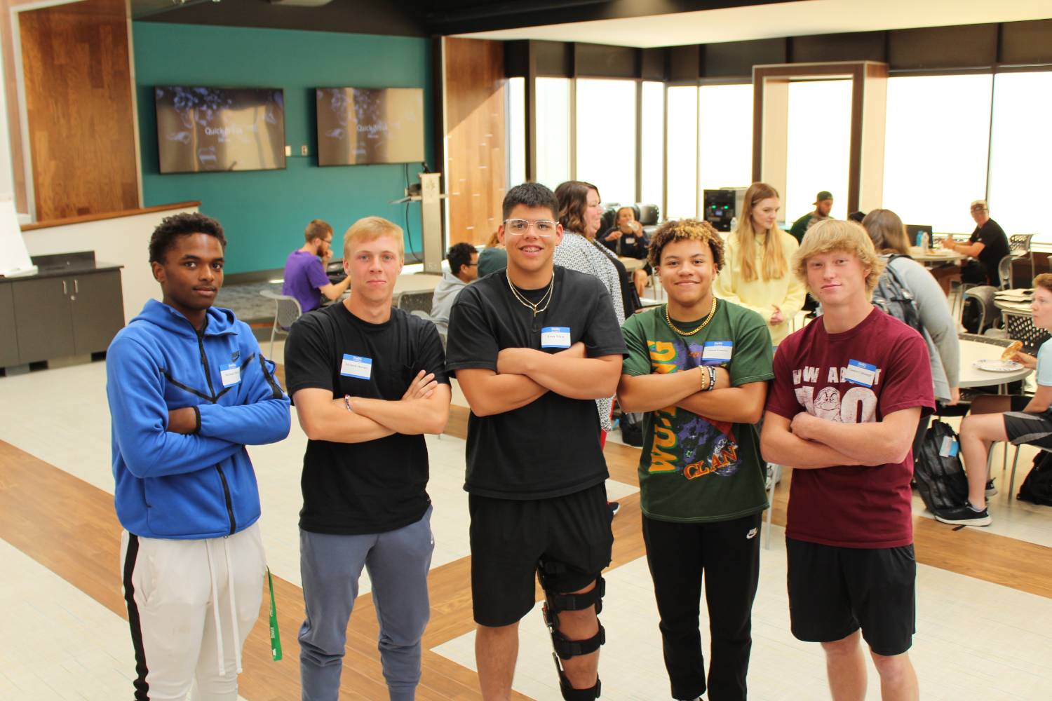 Five male students standing next to each other with their arms crossed