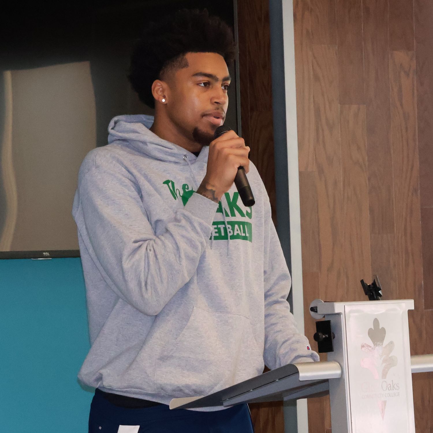 male student holding a microphone, standing at a podium and giving a speech